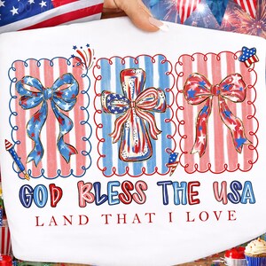May include: White fabric featuring patriotic designs. The design includes three framed illustrations of bows and a cross, all in red, white, and blue. The text "GOD BLESS THE USA LAND THAT I LOVE" is printed below the illustrations.