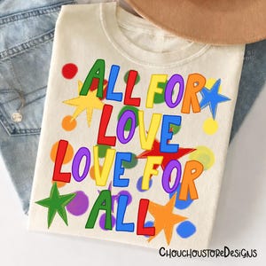 May include: Cream-colored t-shirt with the text "ALL FOR LOVE LOVE FOR ALL" in colorful, block letters. The design includes stars and circles in various colors. The shirt is part of a clothing collection.