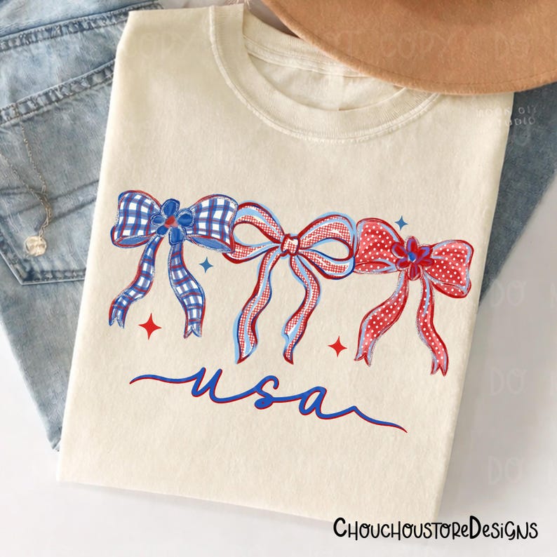 May include: Cream-colored t-shirt featuring three patriotic bows in red, white, and blue. The bows have various patterns, including gingham and polka dots. The word "usa" is written in cursive below the bows. The shirt has the text "ChouchoustoreDesigns" at the bottom.