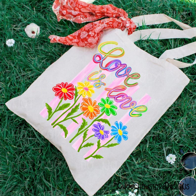 K&ouml;nnte beinhalten: Eine cremefarbene Canvas-Tragetasche mit den Worten "Love is Love" in farbenfroher Schrift. Die Tasche hat ein Blumendesign mit regenbogenfarbenen G&auml;nsebl&uuml;mchen und rosa Streifen. Die Tasche hat cremefarbene Griffe.