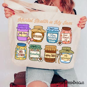 May include: Cream-colored tote bag with the text "Mental Health is My Jam." The bag features illustrations of eight jam jars, each labeled with a mental health concept like "Self-Care" and "Resilience."