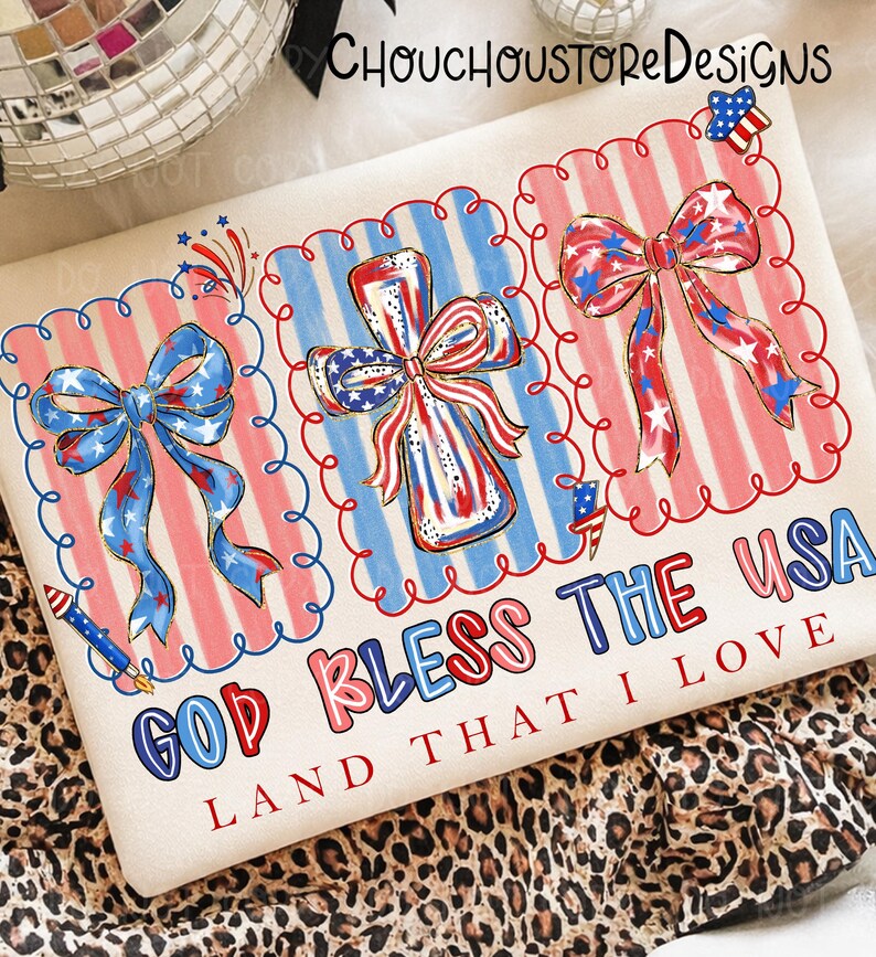 May include: A cream-colored graphic tee featuring patriotic designs. The shirt displays three framed illustrations of bows and a cross, all in red, white, and blue. The text "GOD BLESS THE USA LAND THAT I LOVE" is printed below the illustrations.