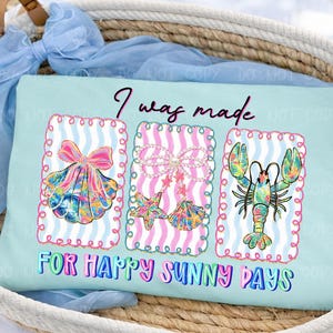 以下が含まれることがあります： 「I was made for happy sunny days」の文字が入った水色のTシャツ。ピンクのリボンが付いた貝殻、ヒトデと真珠の貝殻、カラフルなロブスターの3つのフレームデザインが特徴です。