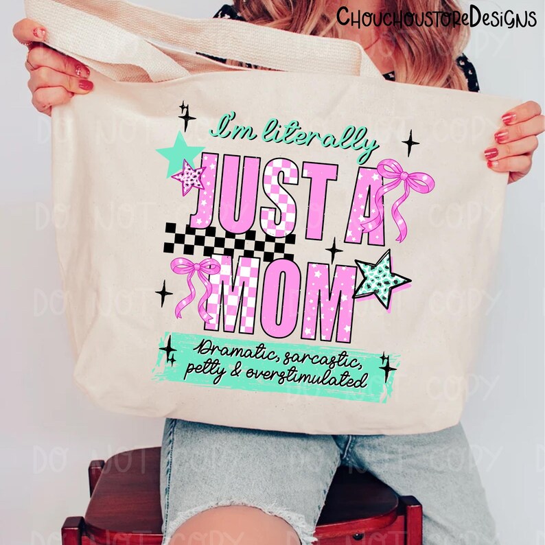 May include: Beige tote bag with the text "I'm literally JUST A MOM" in pink and black, with star and bow accents. The bottom of the bag has the text "Dramatic, sarcastic, petty & overstimulated".