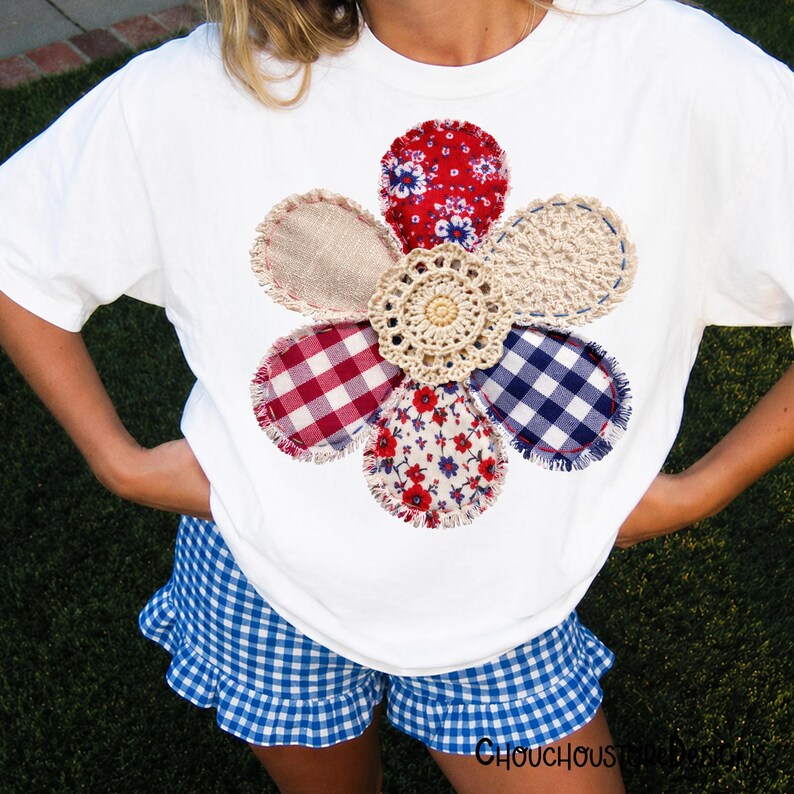 May include: White t-shirt with a large, appliqued flower design. The flower features petals in various fabrics: red floral, gingham, burlap, and crochet. Blue gingham shorts with a ruffled hem. The overall theme is a handmade, country style.
