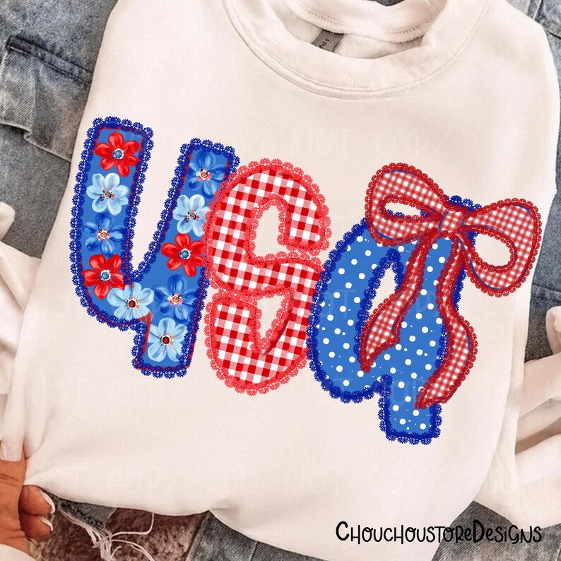 May include: White sweatshirt with a patriotic design. The design features the letters "USA" in red, white, and blue. The "U" is decorated with blue flowers, the "S" is red gingham, and the "A" is blue with white polka dots and a red gingham bow.