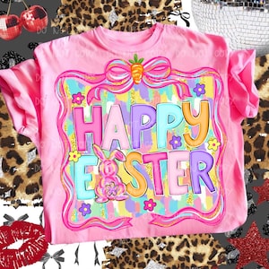 May include: Pink t-shirt with a colorful "Happy Easter" graphic. The design features a bunny, flowers, and a bow with a carrot. The text is in various colors, including pink, blue, and orange. A festive Easter-themed apparel item.