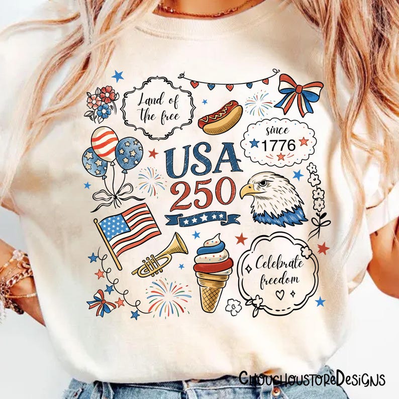 Puede incluir: Camiseta color crema con un dise&ntilde;o patri&oacute;tico que presenta el texto "USA 250" y varias ilustraciones. Incluye una bandera estadounidense, un &aacute;guila, fuegos artificiales y un helado. Tambi&eacute;n est&aacute; presente la frase "Land of the free".