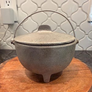 May include: A white ceramic mug with a black handle and the text "But First, Coffee" in a black, bold font. The mug is on a white surface. The mug is likely 11 ounces.