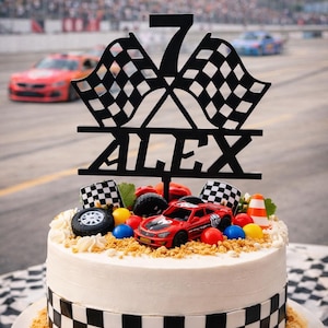 May include: A white cake decorated with a black and white checkered border and a race car theme. The cake is topped with a red race car, checkered flags, and a black sign that says "ALEX" and the number "7".