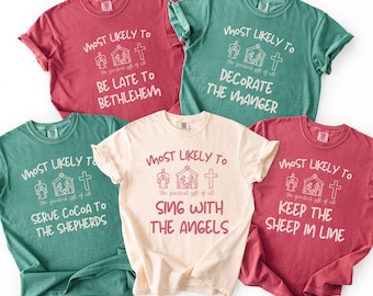 May include: Five short-sleeved t-shirts in various colors, each with a unique Christmas-themed phrase in a script font. The phrases include "Be Late to Bethlehem," "Decorate the Manger," and "Sing with the Angels." Each shirt features a graphic of a nativity scene.