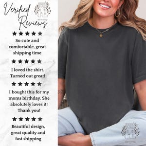 K&ouml;nnte beinhalten: Ein anthrazitfarbenes T-Shirt mit kurzen &Auml;rmeln und Rundhalsausschnitt. Das Bild enth&auml;lt Text mit F&uuml;nf-Sterne-Bewertungen f&uuml;r Blaine Cottage, darunter Kommentare wie So cute and comfortable, I loved the shirt und Beautiful design.