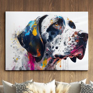 May include: A canvas print featuring a dog's portrait with a white coat, black spots, and colorful paint splatters. The dog's face is detailed with brown eyes and a black nose. The artwork is displayed on a wooden wall above decorative pillows.