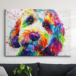 May include: A colourful painting of a dog's face, featuring a mix of bright hues like red, yellow, blue, and purple, set against a white backdrop. The dog has brown eyes and a pink nose, with paint splatters enhancing the artistic style.