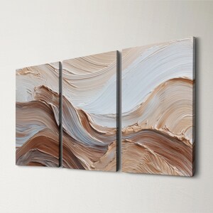 May include: Set of three abstract canvas art panels. The artwork uses textured brushstrokes in brown, beige, and white to create a layered, mountainous effect. The panels are mounted on a white wall, with a neutral colour palette.