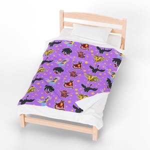 May include: A purple blanket with a repeating pattern of colorful cartoon dragons and yellow stars. The dragons are in various poses and colors, including black, red, blue, and yellow. The blanket is on a small wooden bed with white bedding.