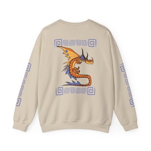 May include: A beige sweatshirt featuring a stylized orange and yellow dragon design on the back. The dragon has blue accents and is framed by blue geometric patterns. Matching patterns are on the sleeves.