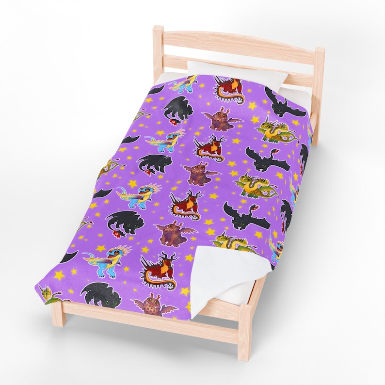 May include: A purple blanket with a repeating pattern of cartoon dragons and yellow stars. The dragons are in various colors, including black, red, green, and blue. The blanket is on a light wood bed frame.