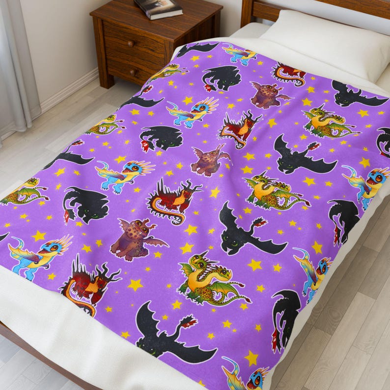 May include: A purple blanket featuring a repeating pattern of colorful cartoon dragons and yellow stars. The dragons are in various poses and colors, including black, green, red, and blue. The blanket is on a bed with a white sheet.