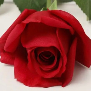 May include: A single, deep red artificial rose with a velvety texture. The rose is closed, with the petals tightly curled around the center.