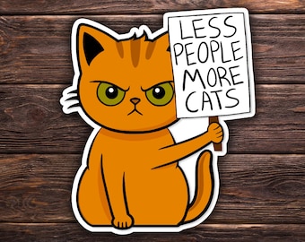 Può includere: Adesivo di un gatto arancione con la scritta "LESS PEOPLE MORE CATS" su un cartello bianco. Il gatto ha gli occhi verdi e un'espressione arrabbiata. Su sfondo di legno.