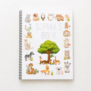 May include: A spiral-bound notebook with a white cover featuring the text SOPHIA'S BOOK in light blue letters. The cover is decorated with a watercolor illustration of a large green tree surrounded by various animals including a tiger, zebra, giraffe, monkey, and koala.