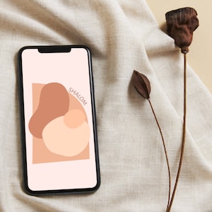 May include: A smartphone with a black case and a white screen displaying a graphic design of abstract shapes in shades of brown and beige. The text "SHALOM" is displayed in black on the screen.