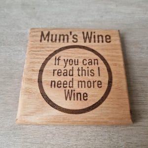 Puede incluir: Un posavasos de madera con el texto "Mum's Wine" y un círculo con el texto "If you can read this I need more Wine".