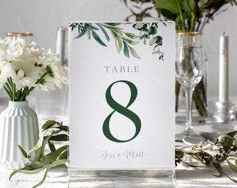 May include: A white table number card with green foliage and the text "TABLE 8 Jess & Matt".