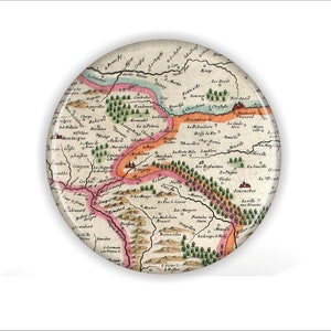 May include: A vintage map of a region in France, featuring a detailed illustration of the area's geography and towns. The map is printed on a circular piece of paper with a white background and is surrounded by a brown border.