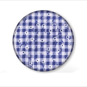 May include: A round, blue and white gingham pattern with small white daisy floral accents. The design is set against a white background. The image is a close-up of a decorative item.