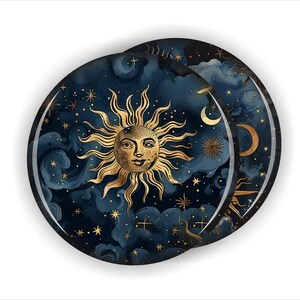 May include: Two round decorative coasters with a celestial design. The coasters feature a gold sun with a face, gold stars, and crescent moons against a dark blue watercolor background. The design evokes a mystical or bohemian theme.