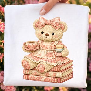May include: An illustration of a teddy bear in a pink floral dress and bow, holding a teacup and macarons. The bear sits on a stack of books with a matching floral pattern. The design has a soft, inviting aesthetic, perfect for children's items.