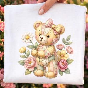May include: A white square with a cute teddy bear illustration. The bear has a patchwork design, a pink bow, and holds a daisy. Pink, yellow, and green floral elements surround the bear, creating a whimsical design.