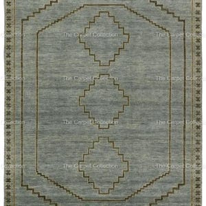 May include: A rectangular, light blue rug with a geometric design. The rug features a central pattern of diamonds and stepped lines in a darker brown color. The border is a repeating star pattern. The text "The Carpet Collection" is repeated around the edges.