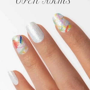 May include: Close-up of a hand with painted nails. The nails feature a mix of designs, including solid white glitter and colorful abstract art. The text "OPEN ARMS" is displayed in elegant script above the hand.