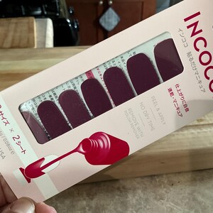 May include: A package of INCOCO nail polish strips in a burgundy color. The package includes 8 sizes and 2 sheets, with a net weight of 2.4g/0.08oz. The packaging features Japanese text and a graphic of a nail polish bottle.