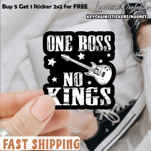 May include: A white ceramic mug with a black handle and the text "But First, Coffee" in a black, bold font. The mug is on a white surface. The mug is approximately 4 inches tall.