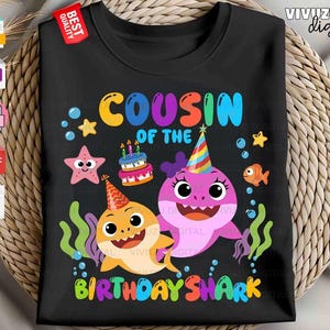 Puede incluir: Una camiseta negra con un gr&aacute;fico colorido y el texto "COUSIN OF THE BIRTHDAY SHARK". El dise&ntilde;o incluye dos tiburones de dibujos animados con gorros de fiesta, un pastel de cumplea&ntilde;os con velas encendidas, una estrella de mar rosa y burbujas.