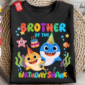 Puede incluir: Una camiseta negra con un gr&aacute;fico colorido y el texto BROTHER OF THE BIRTHDAY SHARK. El dise&ntilde;o incluye dos tiburones de dibujos animados con gorros de fiesta, un pastel de cumplea&ntilde;os con velas, una estrella de mar rosa y algas verdes.
