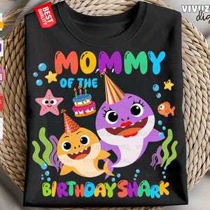 Puede incluir: Una camiseta negra con un gr&aacute;fico colorido y el texto Mommy of the Birthday Shark. El dise&ntilde;o incluye un tibur&oacute;n amarillo y uno morado con gorros de fiesta, un pastel de cumplea&ntilde;os, una estrella de mar, un peque&ntilde;o pez naranja y algas marinas.