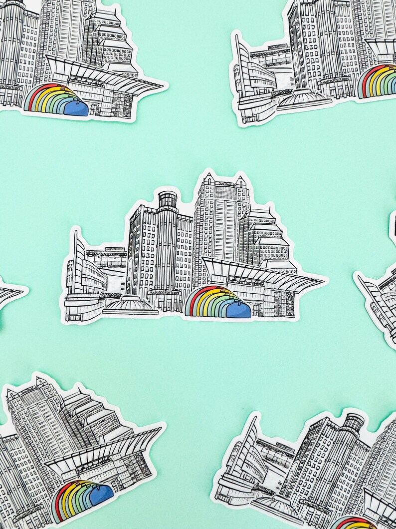 Puede incluir: Un conjunto de cinco pegatinas que muestran una ilustraci&oacute;n en blanco y negro de un horizonte de ciudad con un arco&iacute;ris sobre los edificios. Las pegatinas est&aacute;n sobre un fondo azul claro.