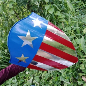 May include: A red, white, and blue shield with a silver star design. The shield is made of metal and has a shiny finish.