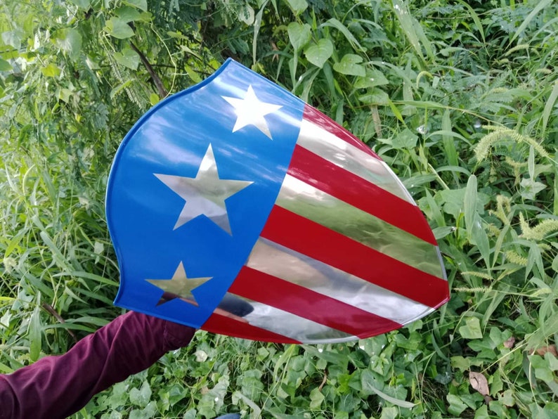 May include: A red, white, and blue shield with a silver star design. The shield is made of metal and has a shiny finish.