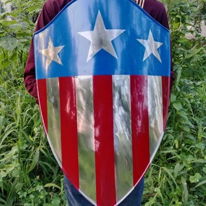 May include: A red, white, and blue shield with five stars. The shield is made of metal and has a shiny finish.