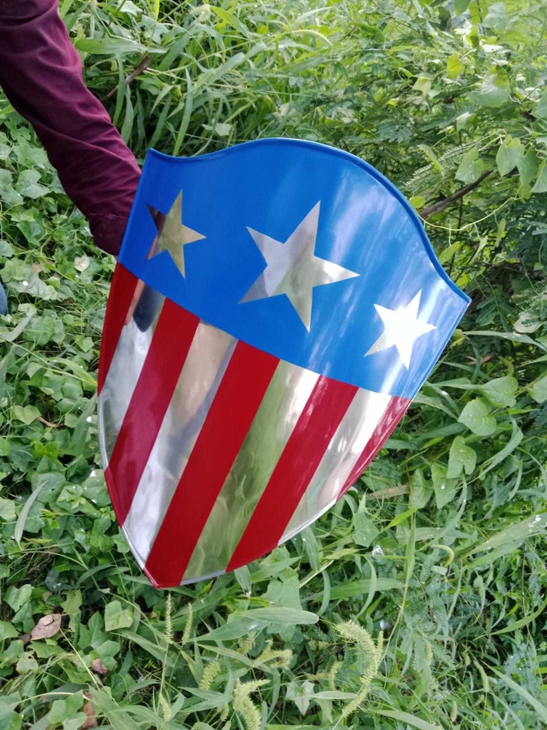 May include: A red, white, and blue shield with a silver star design. The shield is made of metal and has a shiny finish.