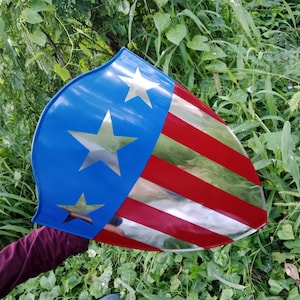 May include: A red, white, and blue shield with a silver star design. The shield is made of metal and has a glossy finish.
