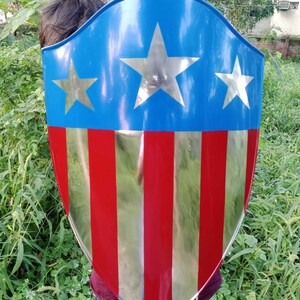 May include: A red, white, and blue shield with five pointed stars. The shield is made of metal and has a shiny finish.