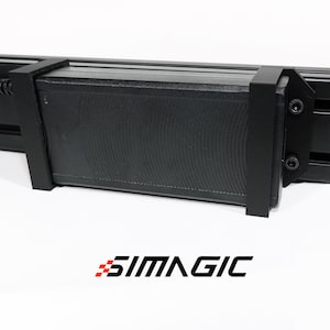 May include: Black rectangular device with a textured surface and a bracket, possibly a component of a larger system. The word "SIMAGIC" is printed in black and red at the bottom.