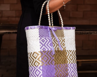 Handwoven Artisan Bag made of recycled plastic in white, lilac and gold tones with lilac ribbon details.